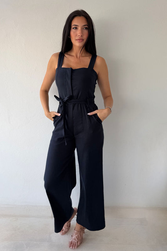 Model wearing the Navy Harbor Jumpsuit featuring a square neckline, self-tie waist, and wide-leg silhouette in navy.