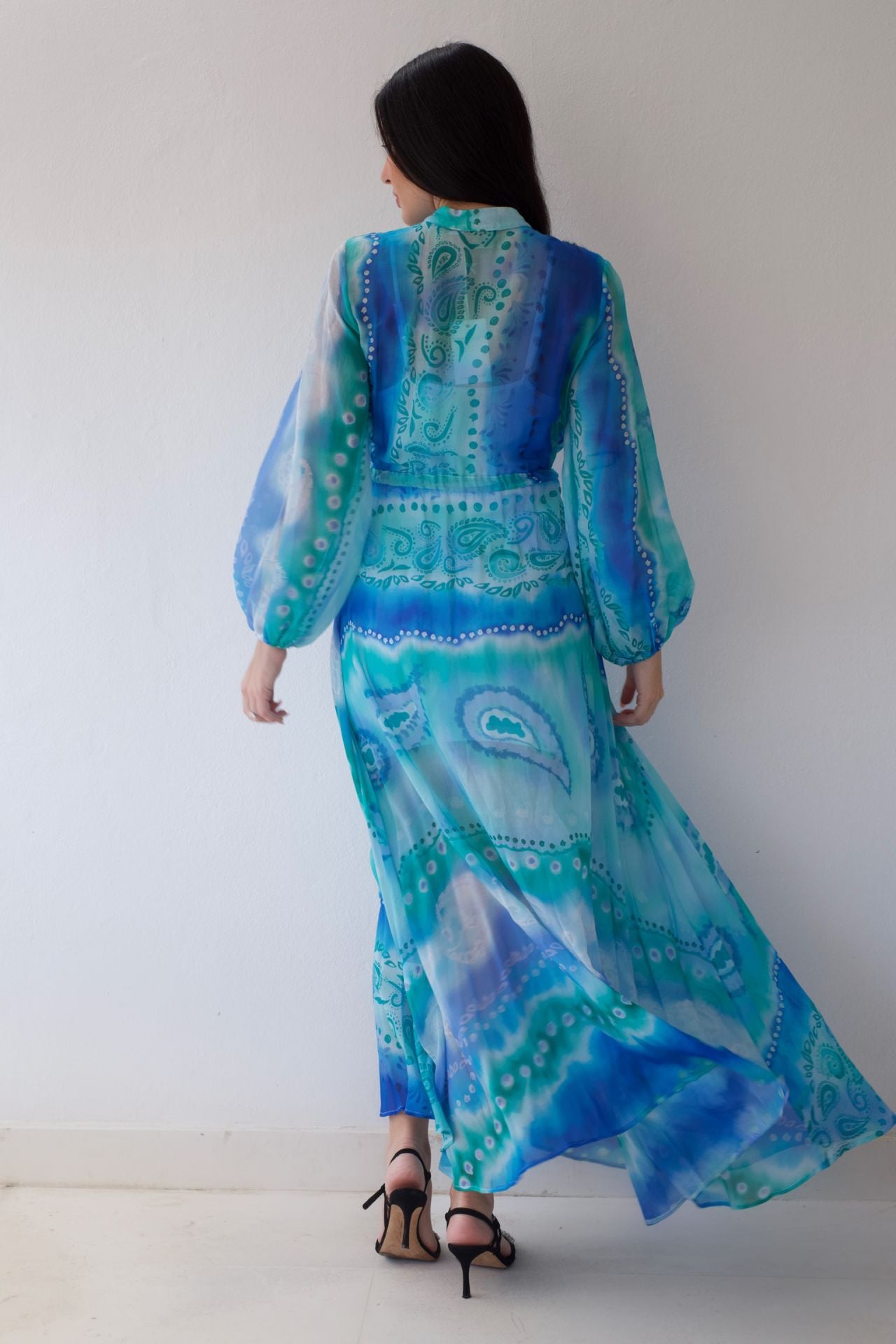Woman wearing a blue and green patterned dress against a white background
