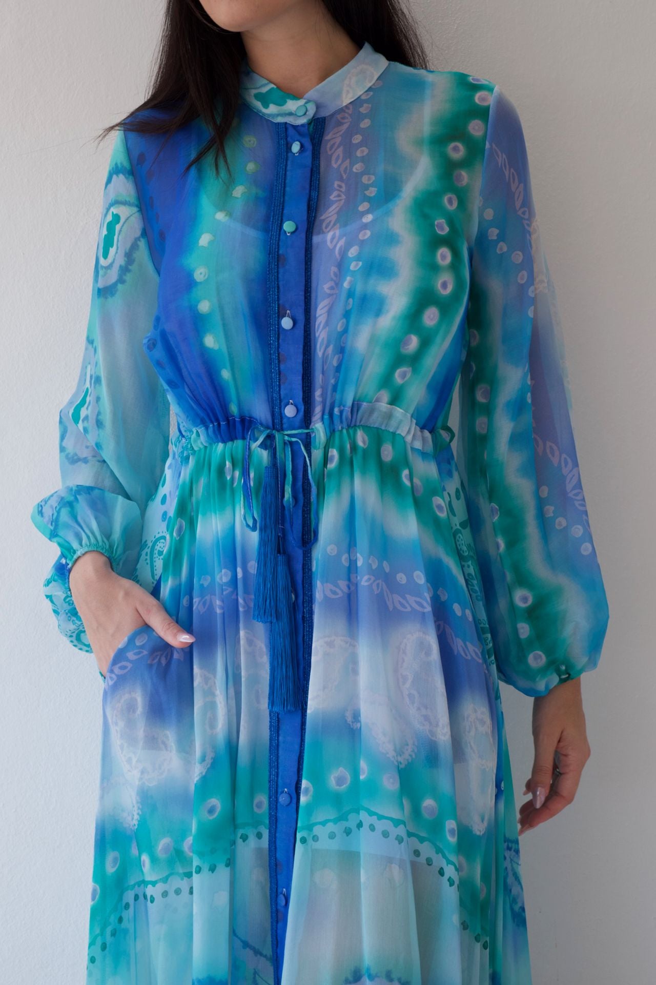 Woman wearing a blue and green patterned dress against a plain background