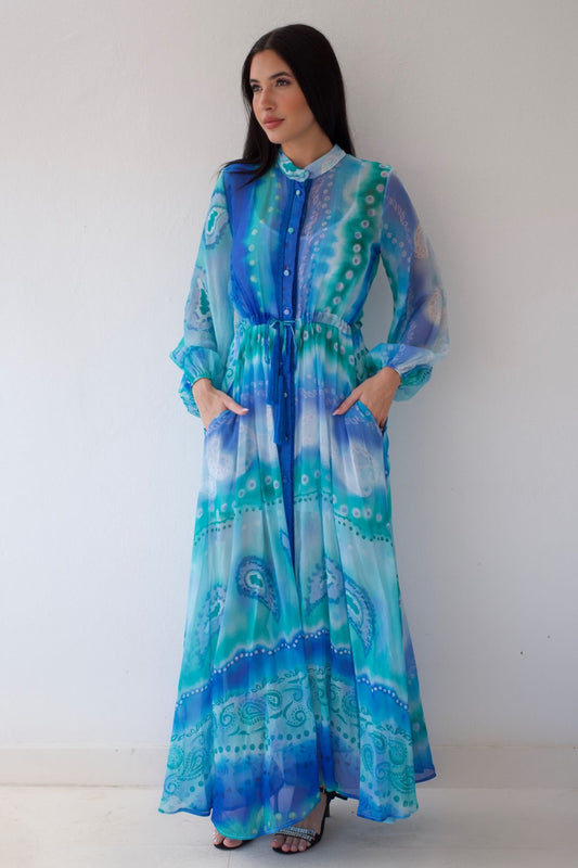 Woman wearing a long, patterned dress with blue and green colors against a white background
