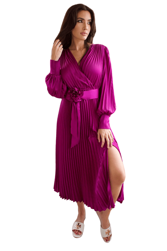A model wearing a magenta pleated v-neck satin dress with long bubble sleeves and a floral detail on the belt, paired with open-toe heels.