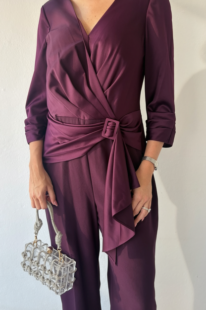 Closeup of the Plum Elegance Jumpsuit with V-neckline, draped buckle waist, three-quarter sleeves and wide-leg silhouette.