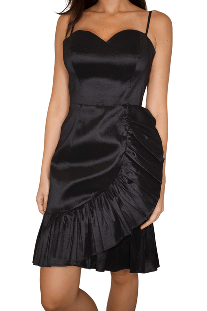 Closeup of a woman wearing a classic black ruffle front cocktail dress with spaghetti straps and a heart-shaped front.