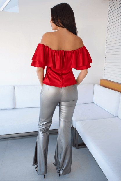Back view of women's red off-the-shoulder top, showcasing its sleek design and elegant draping.

