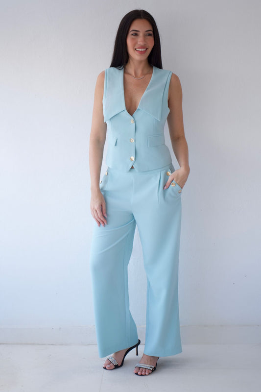 Woman wearing a mint sleeveless top and pants set against a white background