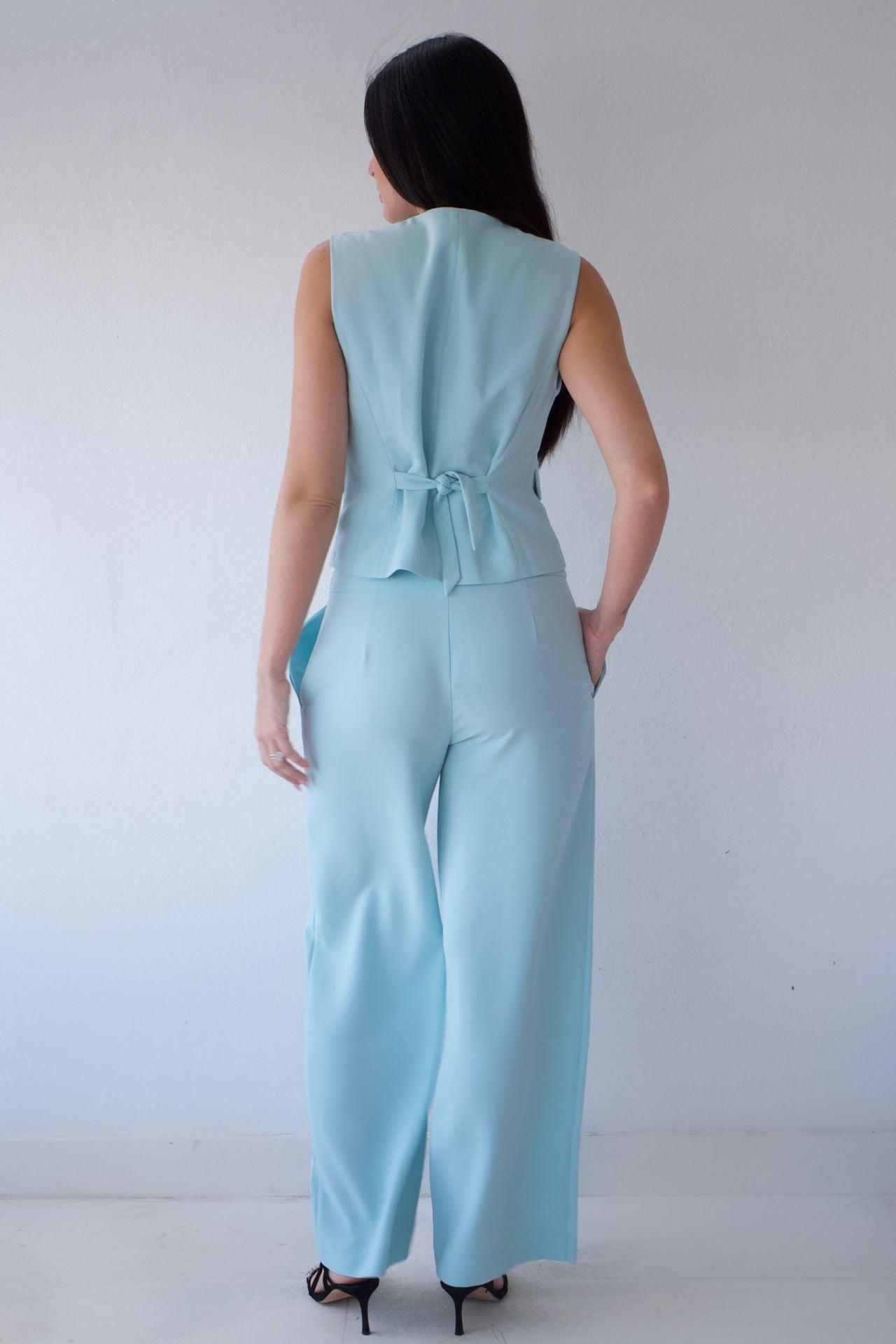 Woman wearing a mint pant set against a plain background