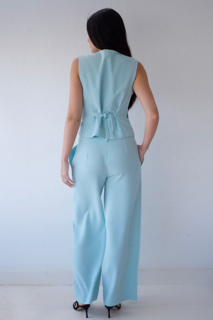Woman wearing a mint pant set against a plain background