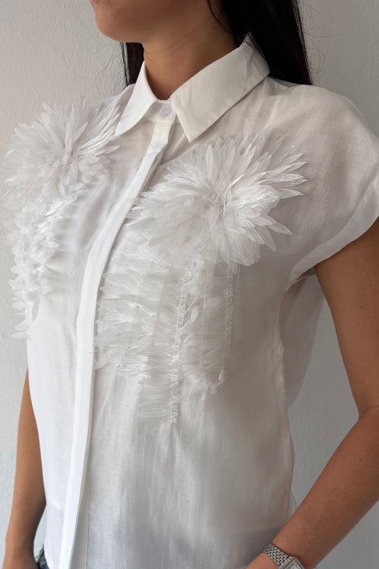 Model wearing the White Blossom Statement Blouse featuring three-dimensional floral appliqué details, short sleeves, and a coordinating camisole.