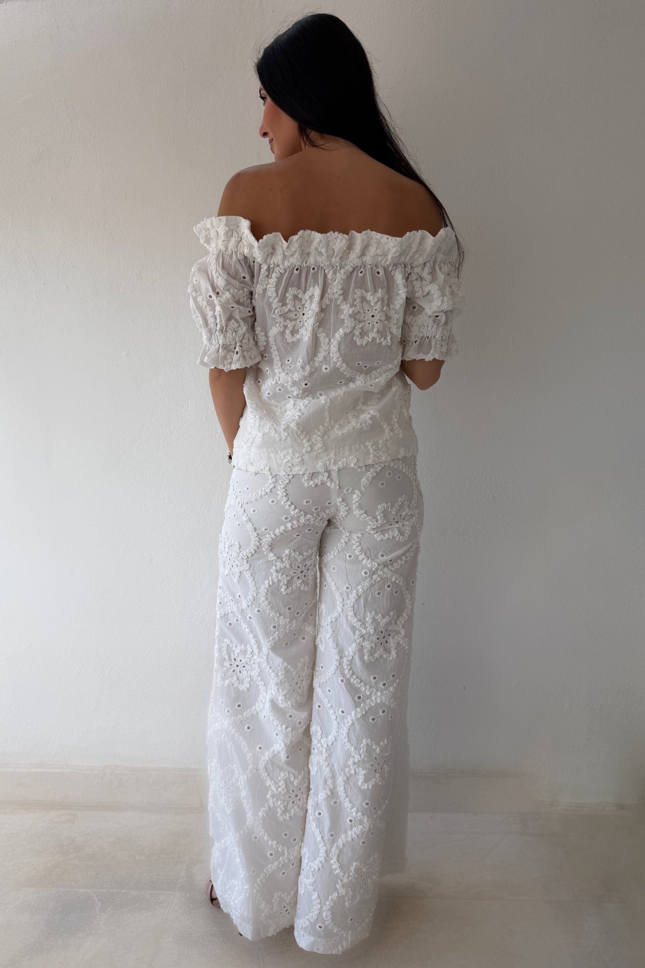 Model wearing the White Romance Set featuring an off-the-shoulder embroidered top and matching wide-leg pants in white cotton.