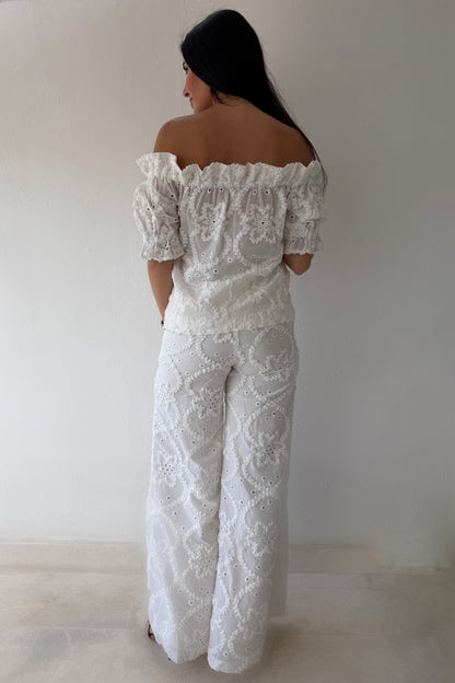 Model wearing the White Romance Set featuring an off-the-shoulder embroidered top and matching wide-leg pants in white cotton.