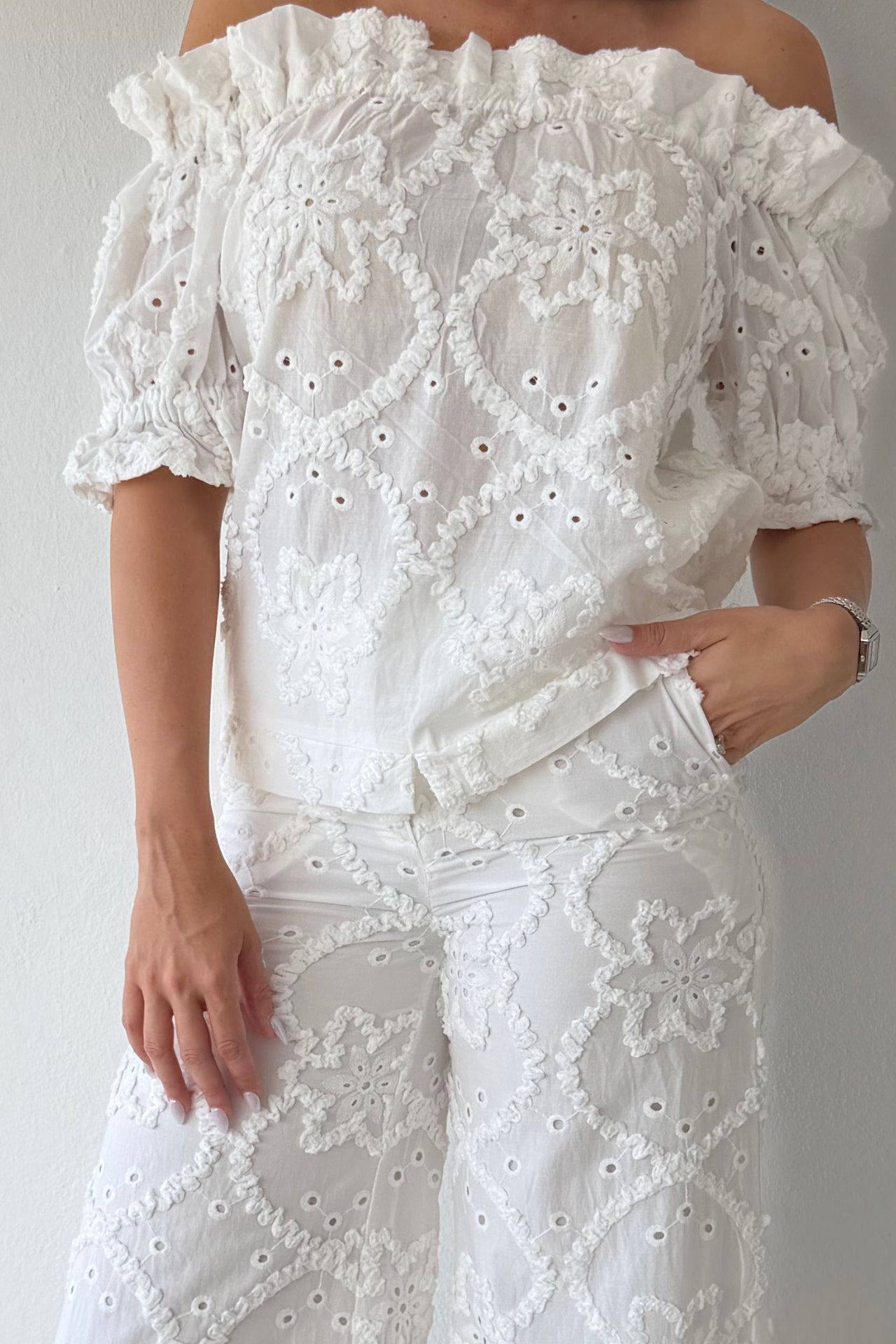 Model wearing the White Romance Set featuring an off-the-shoulder embroidered top and matching wide-leg pants in white cotton.