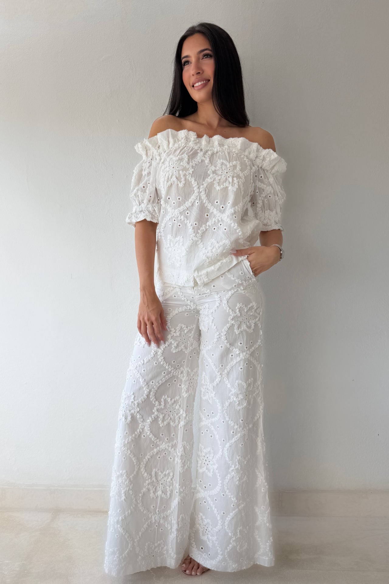 Model wearing the White Romance Set featuring an off-the-shoulder embroidered top and matching wide-leg pants in white cotton.