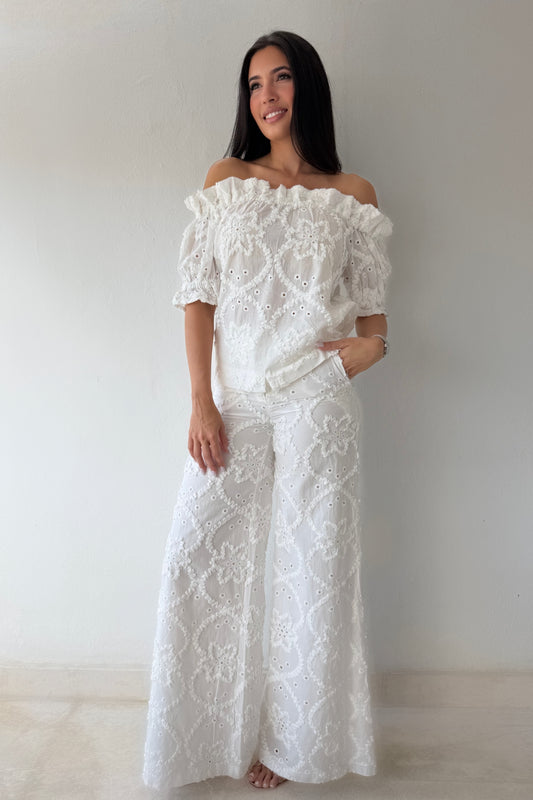 Model wearing the White Romance Set featuring an off-the-shoulder embroidered top and matching wide-leg pants in white cotton.