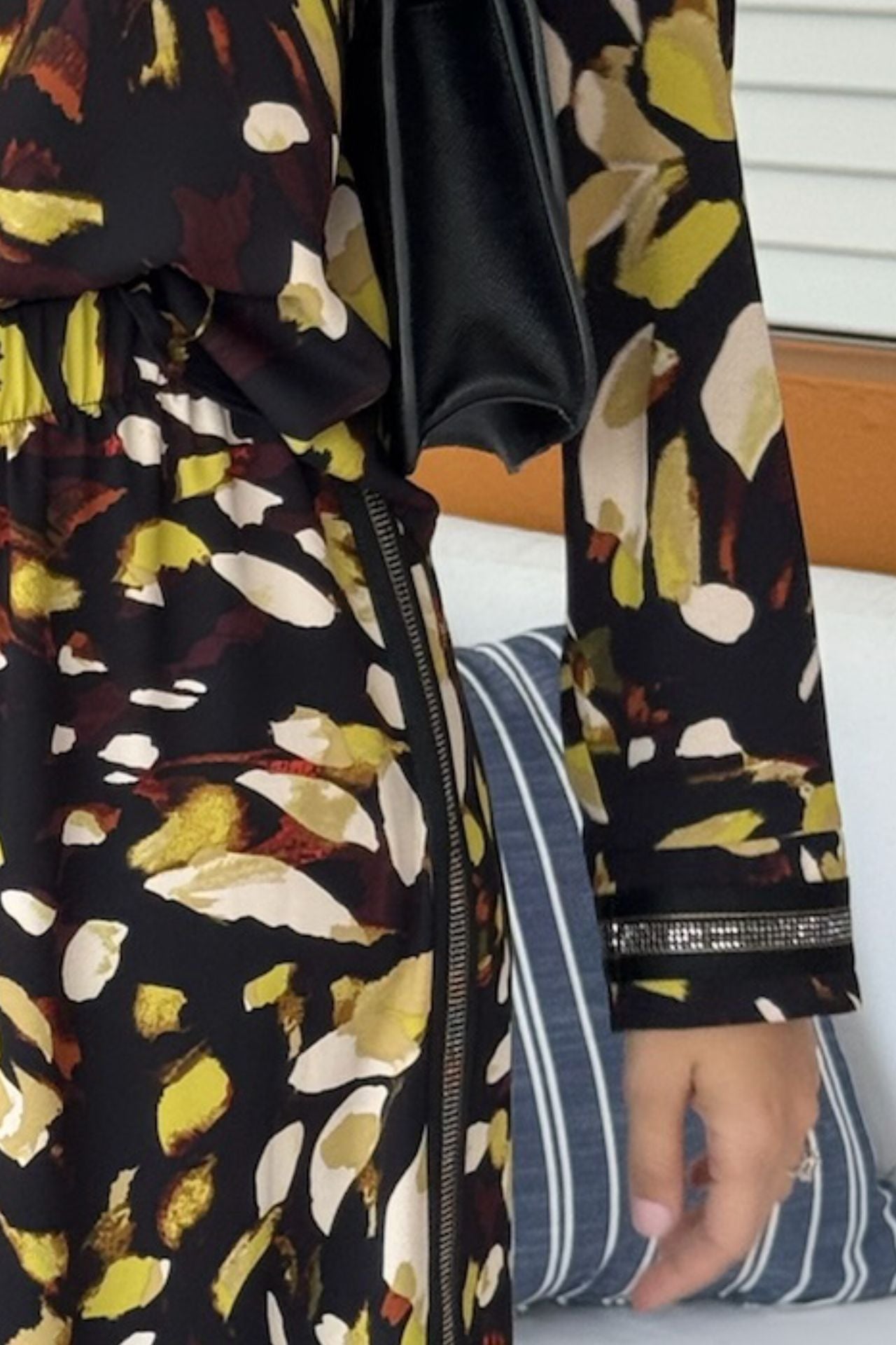 Closeup of a woman wearing a satin abstract print tunic and wide-leg pull-on pant set in black and yellow with shimmer trim details