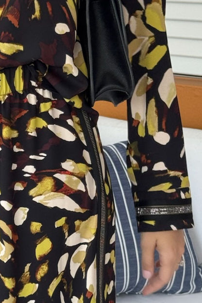 Closeup of a woman wearing a satin abstract print tunic and wide-leg pull-on pant set in black and yellow with shimmer trim details