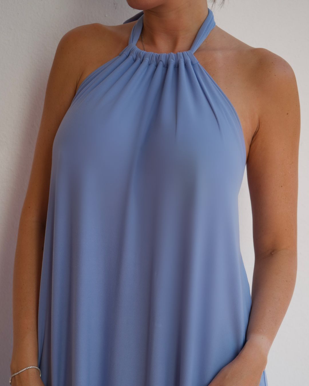 Close-up of halter neckline and soft drape fabric on baby blue maxi dress, lightweight wrinkle-free stretch material
