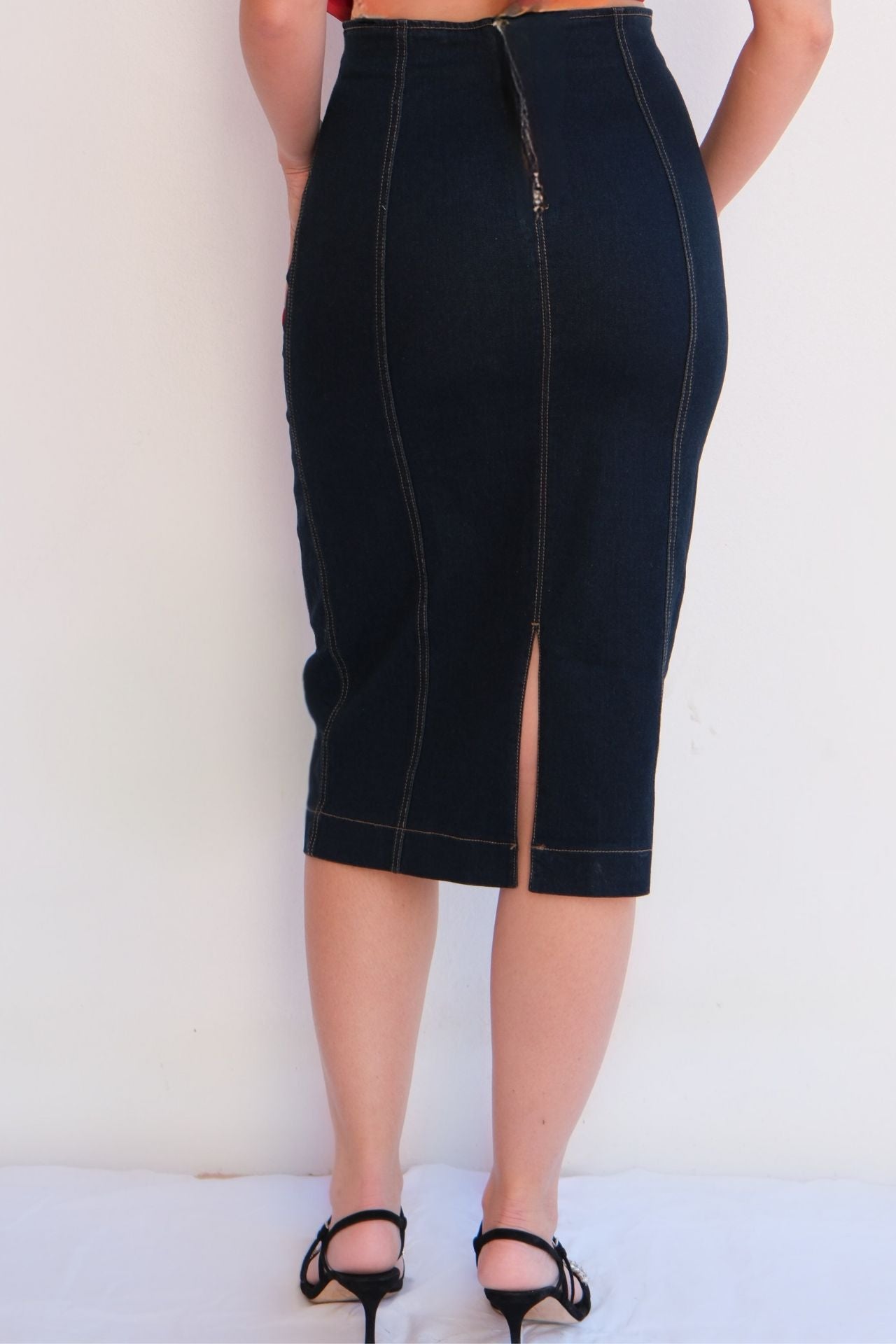 Back view elegant dark denim pencil skirt with contrast stitching, styled with a red strapless top for a chic day-to-night look.