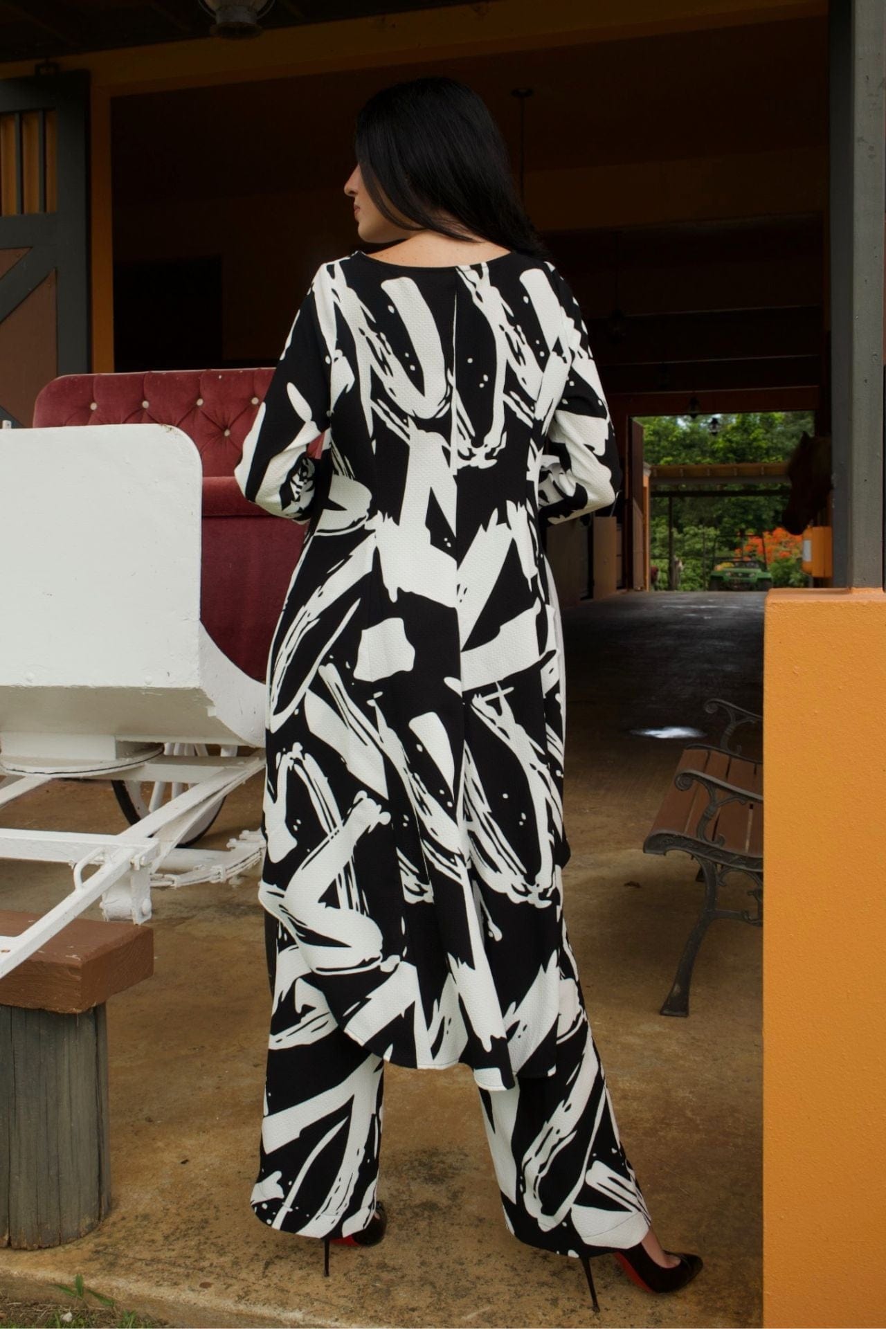 Woman wearing black and white abstract print high-low tunic set with matching wide-leg pants-back view.


