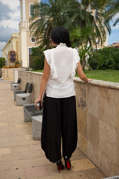 Back view of a woman wearing black baggy cropped pants with elastic waist and wrinkle-free fabric.