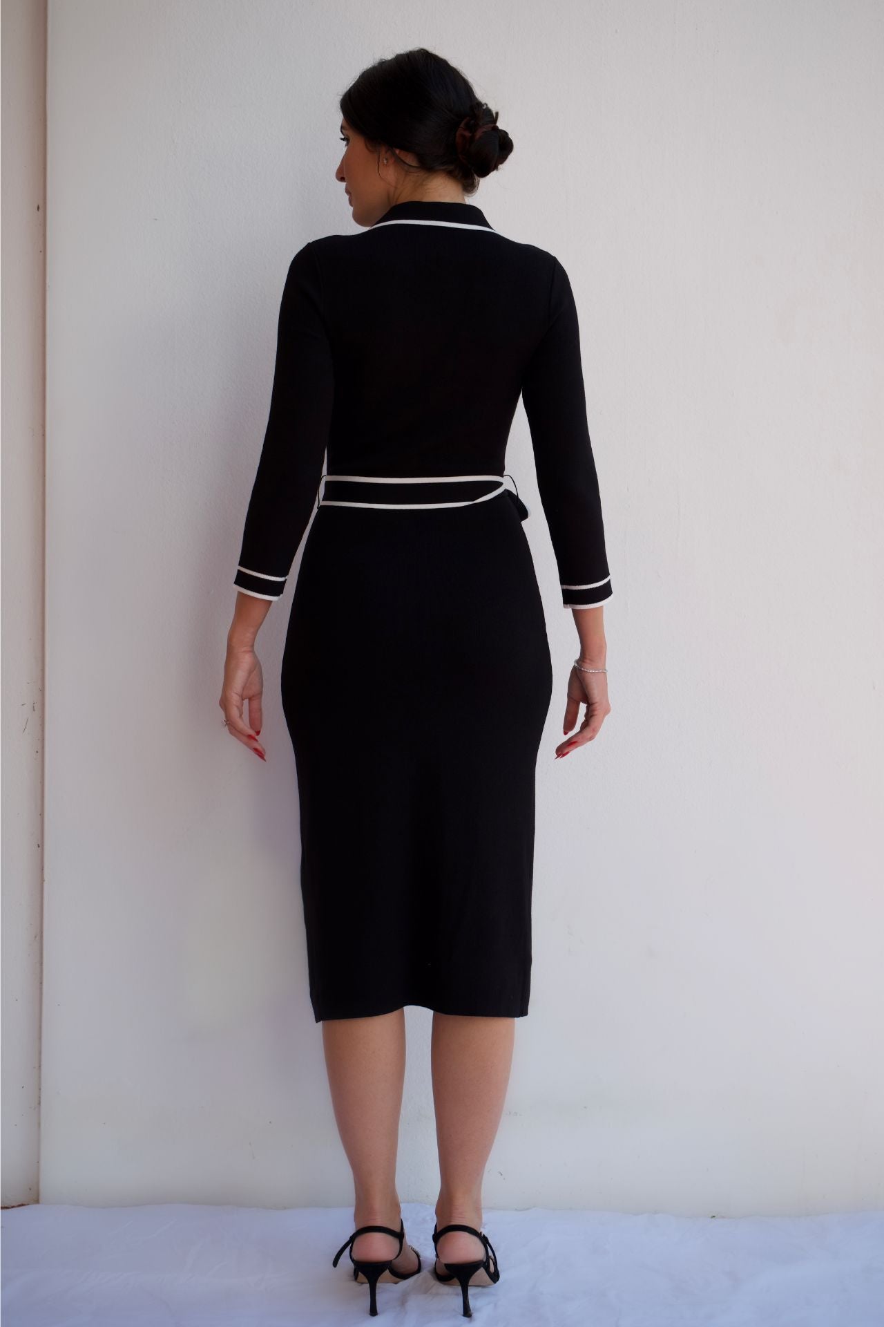 Back view of black midi shirt dress with white contrast trim, button front, and waist tie, styled for an elegant day-to-night look.