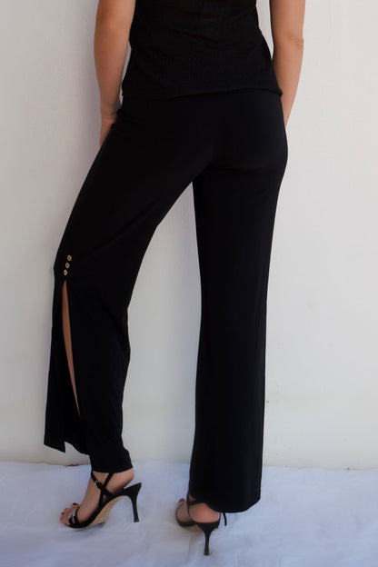 Black pull-on dressy pants with gold button side slit detail and elegant wrinkle-free stretch fabric styled for evening wear-back view