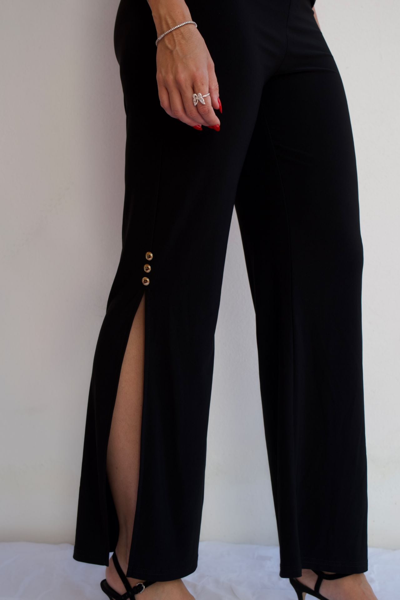 Black pull-on dressy pants with gold button side slit detail and elegant wrinkle-free stretch fabric styled for evening wear-closeup view