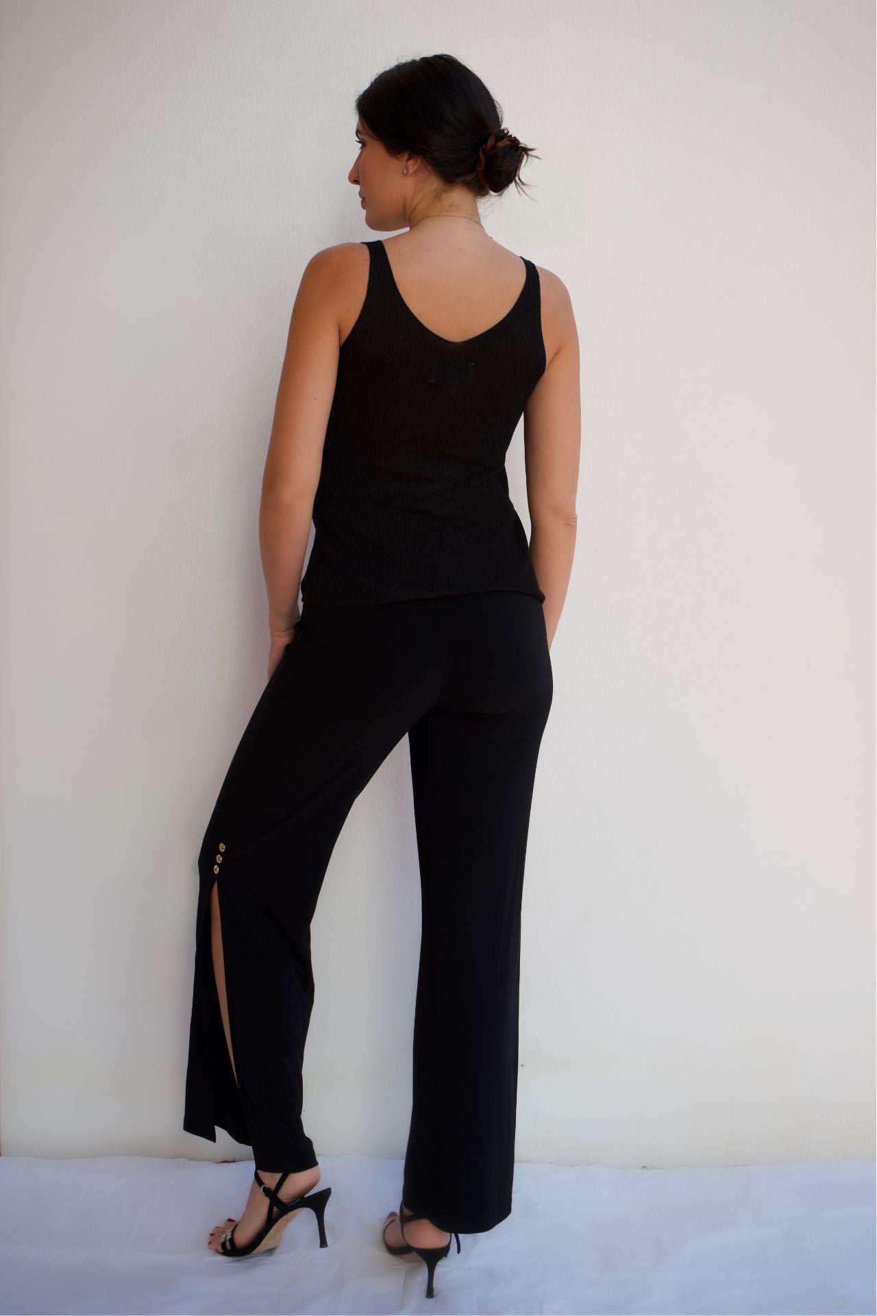 Black shimmer knit sleeveless tank top with subtle sparkle, elegant stretch evening blouse styled with black pants back view
