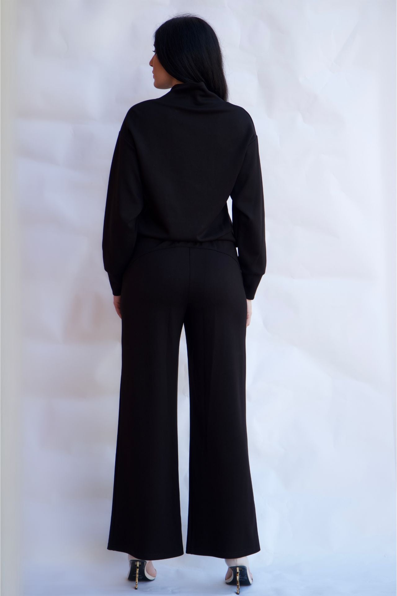 Black sporty chic travel lounge set with zip neck top and wide leg pants styled with heels available online and in-store
