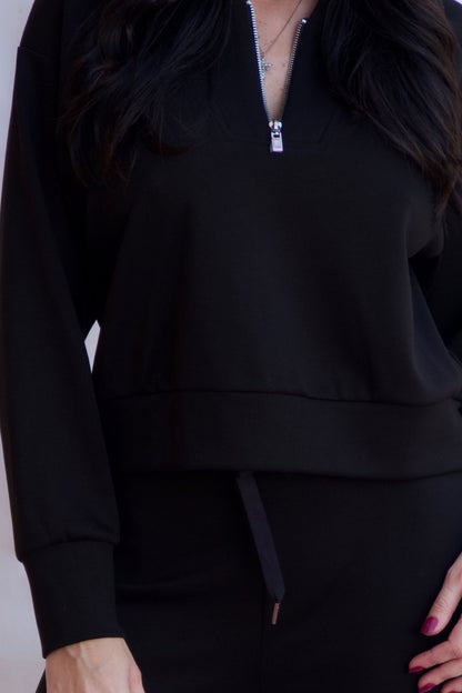 Black sporty chic travel lounge set with zip neck top and wide leg pants styled with heels available online and in-store