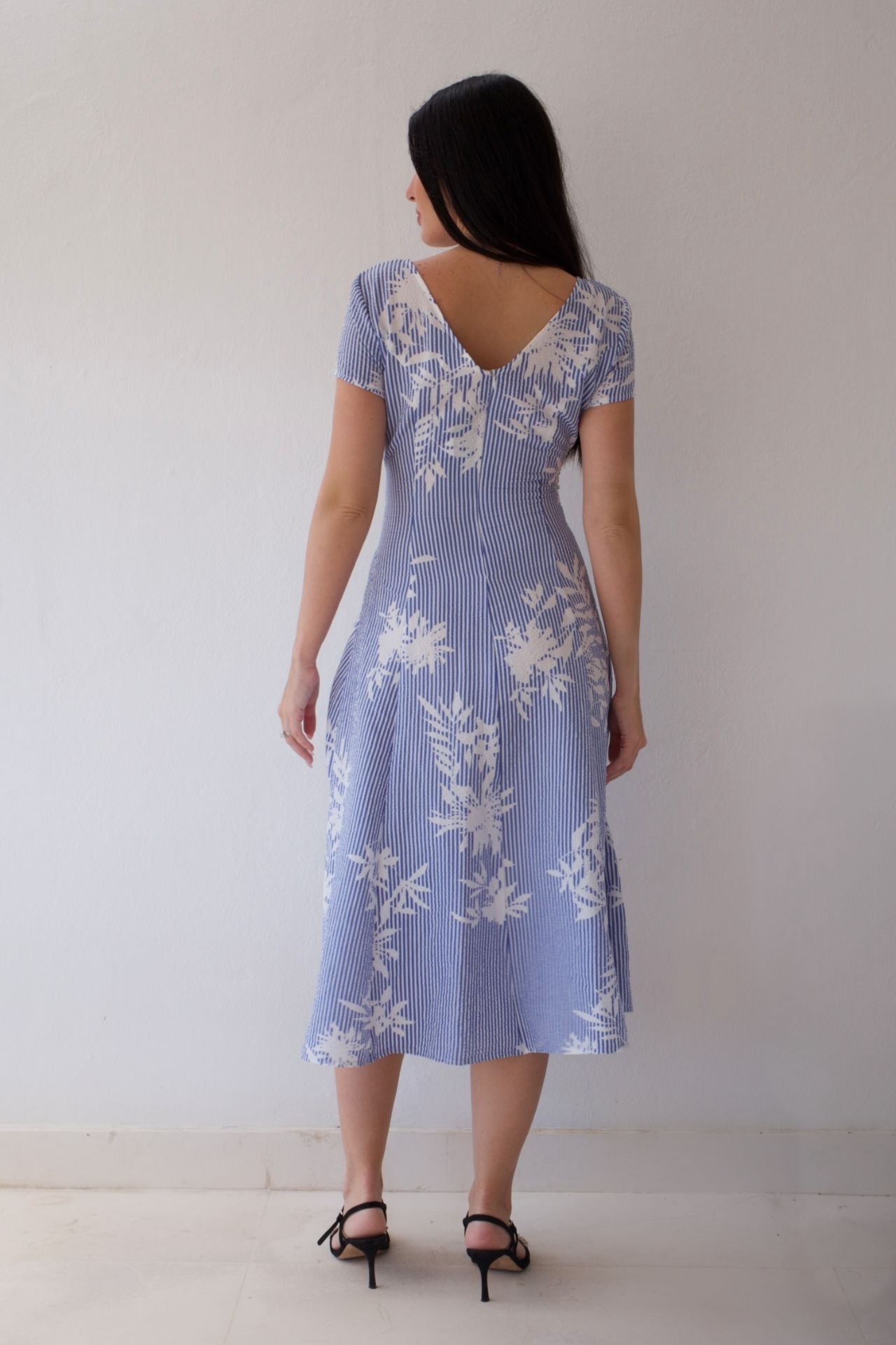 Woman wearing a blue floral dress against a plain background