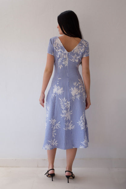 Woman wearing a blue floral dress against a plain background