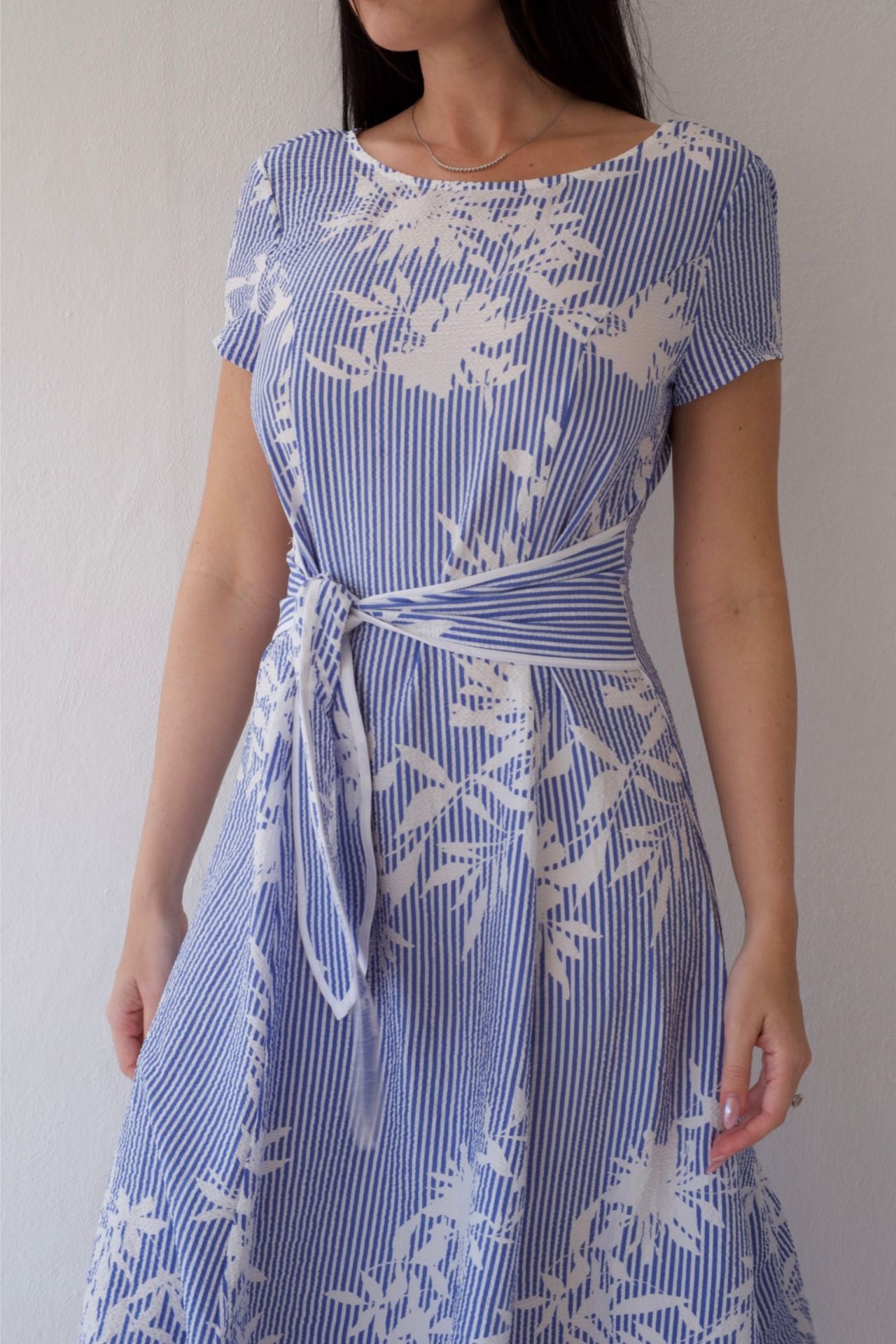 Woman wearing a blue and white patterned dress against a plain background