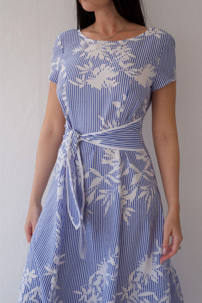 Woman wearing a blue and white patterned dress against a plain background