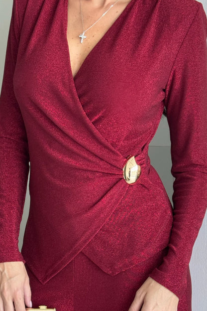 Back view of a woman wearing a burgundy long-sleeve knot-detail wide-leg jumpsuit standing indoors.