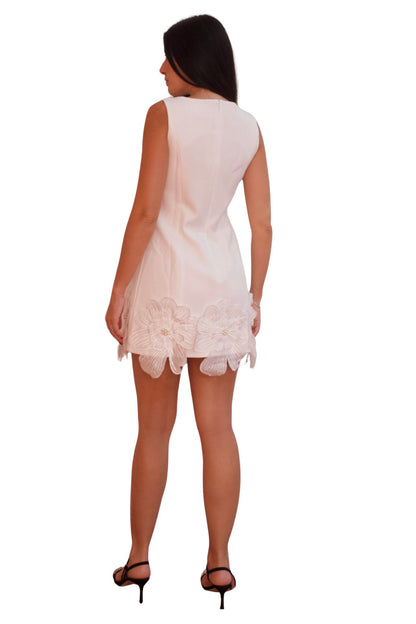 White cocktail dress with 3D floral appliqué and scalloped hem, elegant sleeveless mini dress for special occasions.
