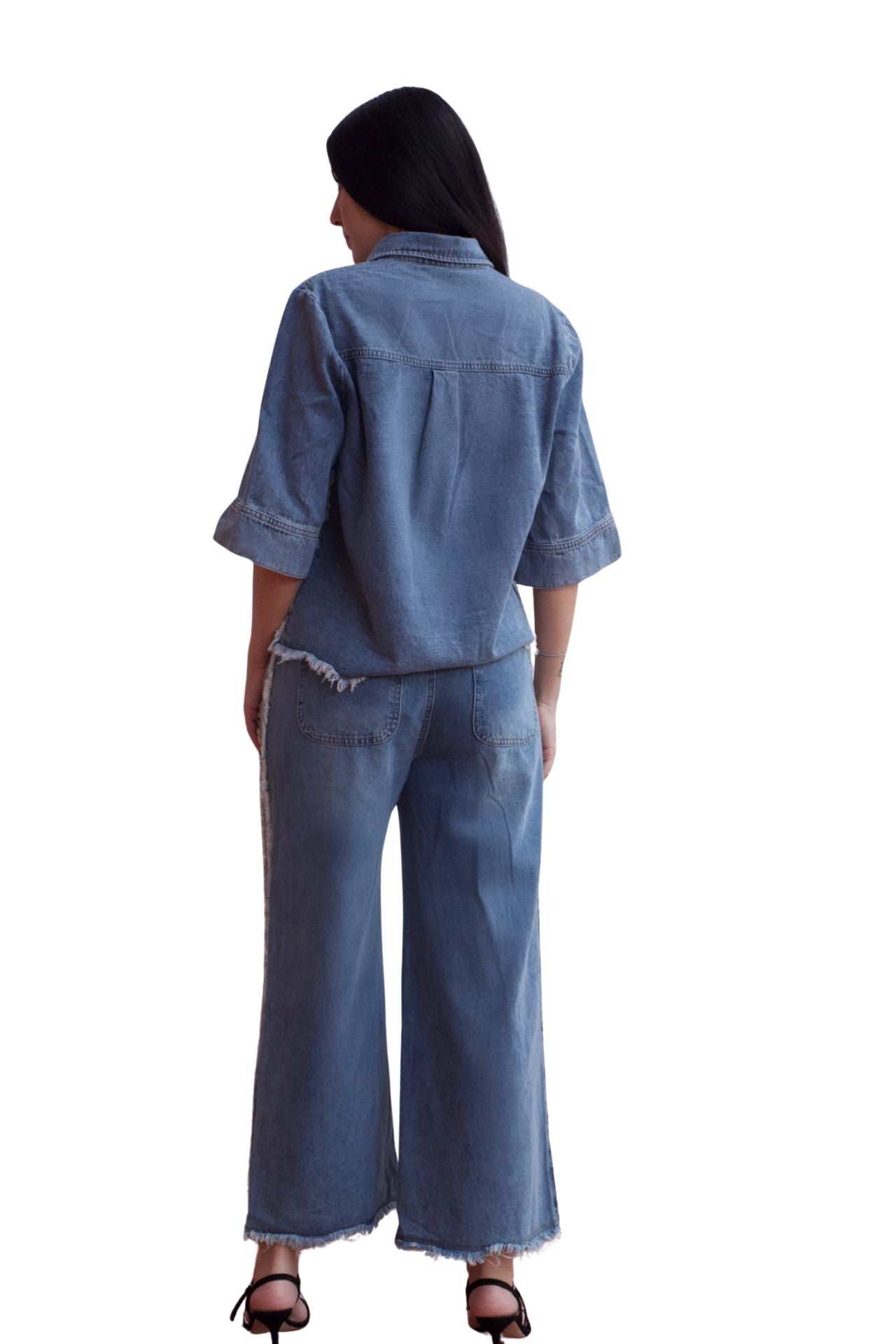 Woman wearing a two-piece denim set with frayed hem shirt and wide-leg cropped pants.