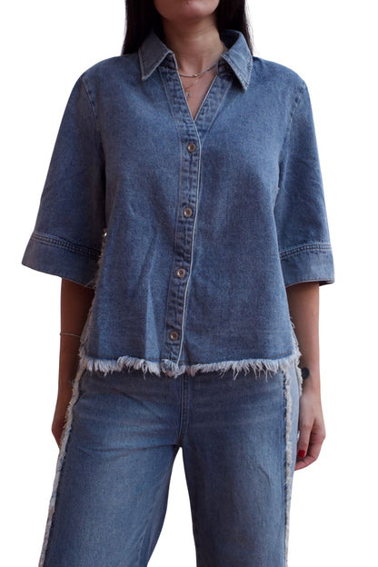 Woman wearing a two-piece denim set with frayed hem shirt and wide-leg cropped pants.