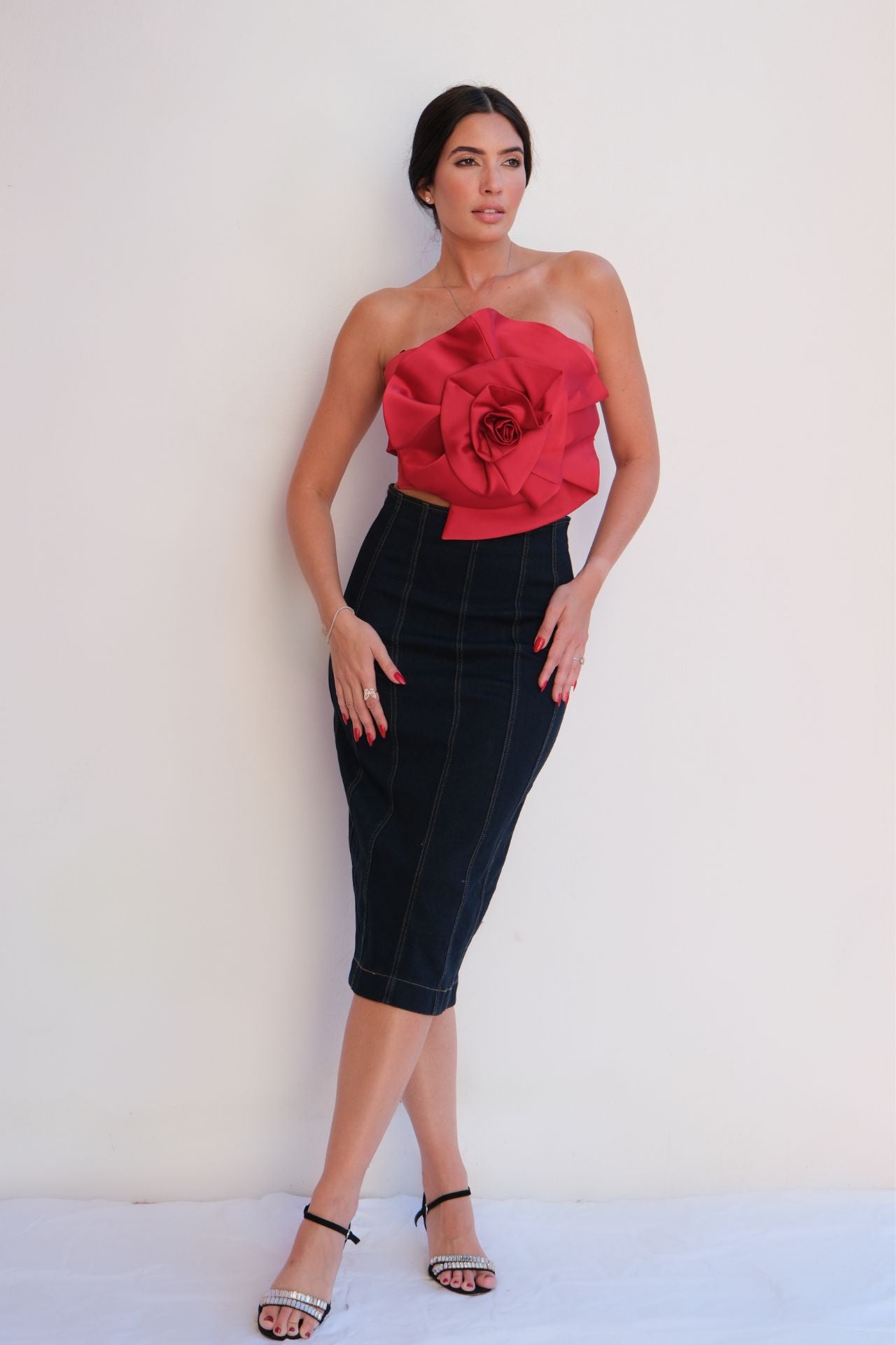 Elegant dark denim pencil skirt with contrast stitching, styled with a red strapless top for a chic day-to-night look.