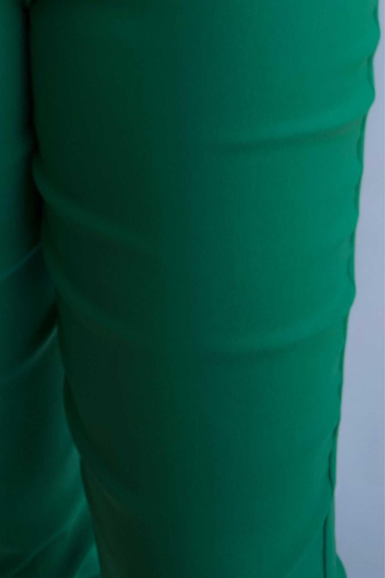 Emerald green tailored pull on pants with front pockets and silver buttons closeup.