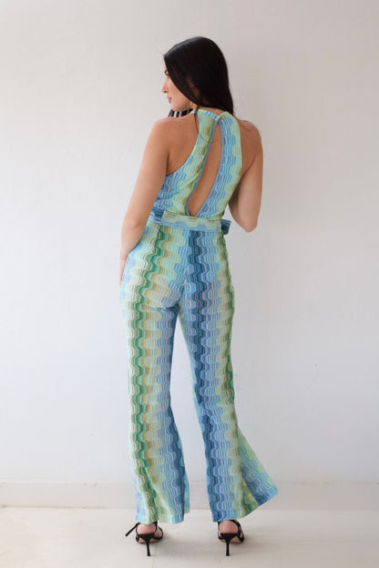 Woman wearing a blue and green patterned jumpsuit against a white background