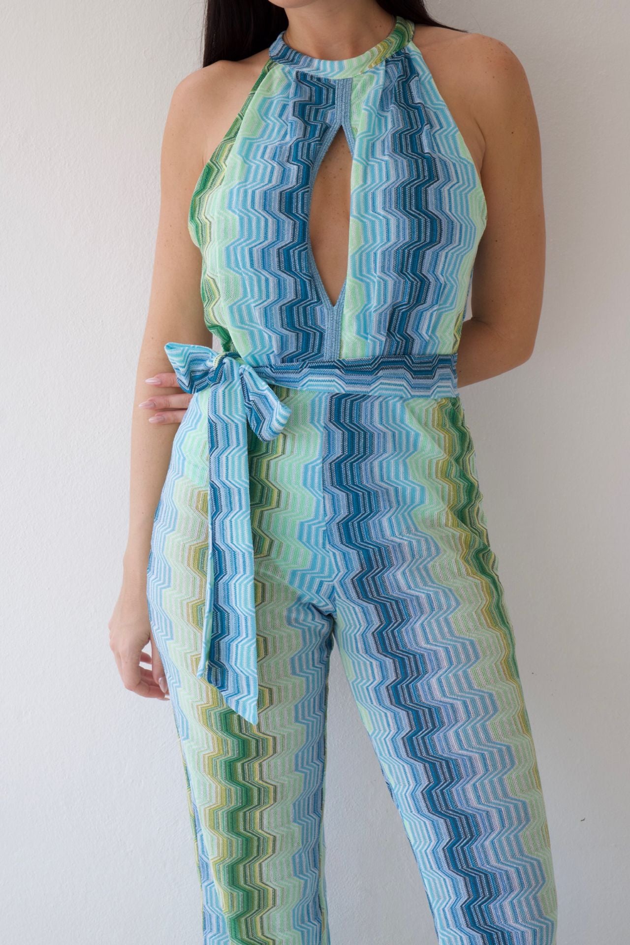 Woman wearing a blue and green patterned jumpsuit against a white background