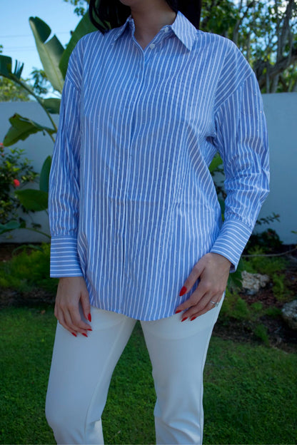 Model wearing light blue striped blouse with shimmer accents and white pants — casual chic look Elegance Boutique