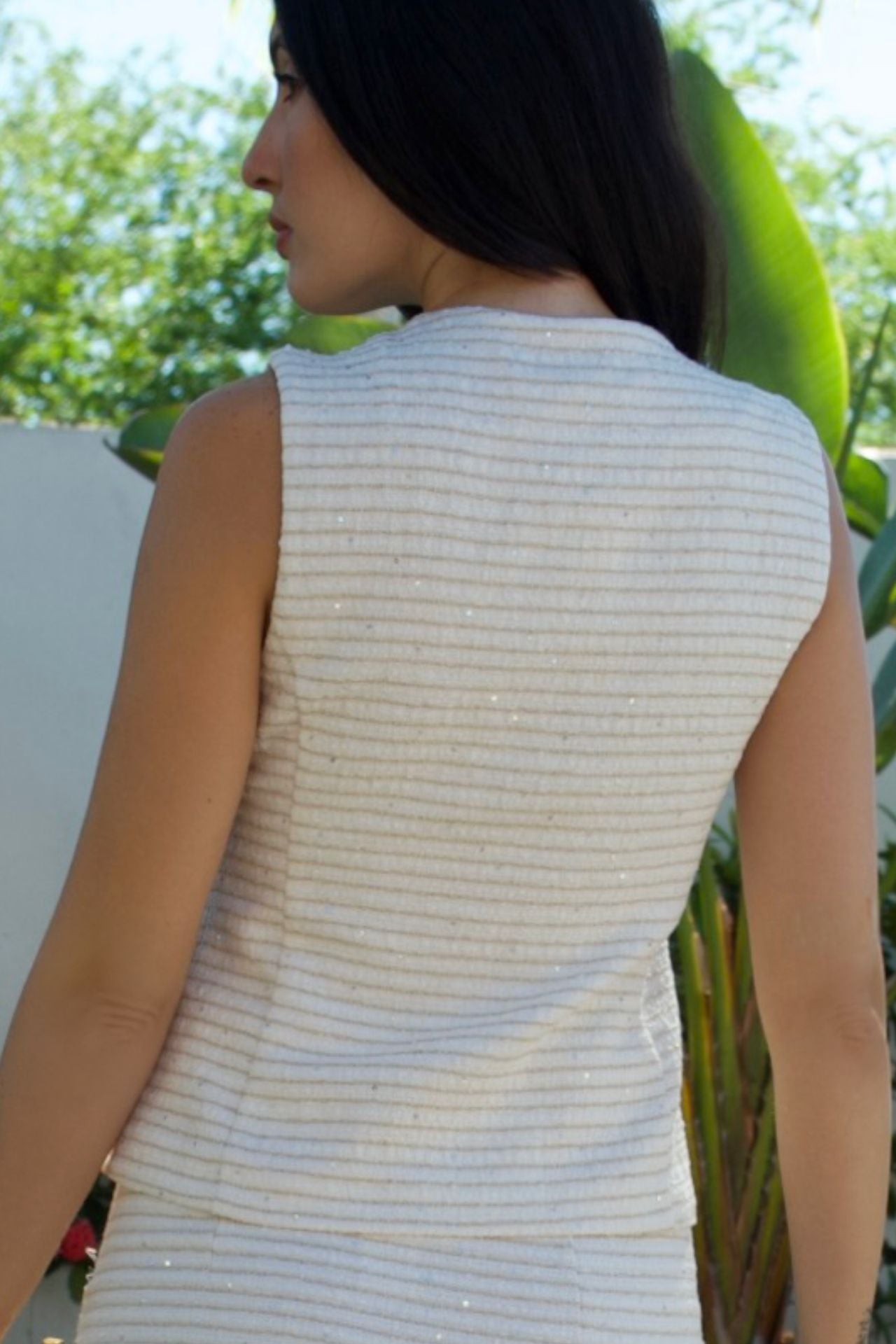 Close-up of back ivory textured sleeveless vest with metallic accents and gold buttons — Elegance Boutique