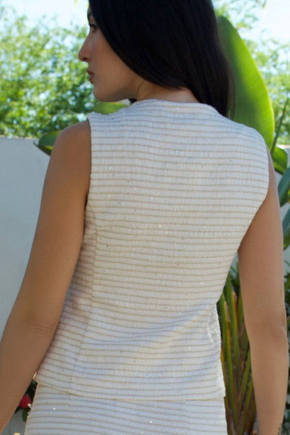 Close-up of back ivory textured sleeveless vest with metallic accents and gold buttons — Elegance Boutique