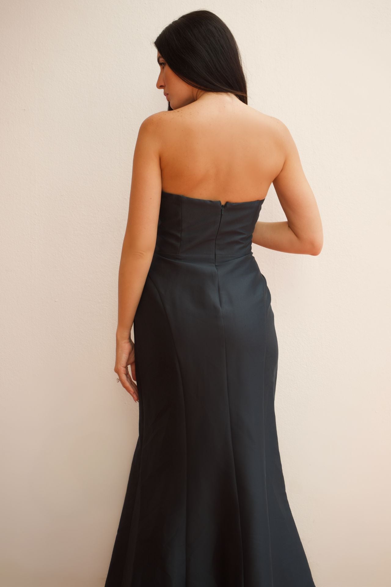 Model wearing a midnight green strapless evening dress with floral appliqué detailing and fitted silhouette.