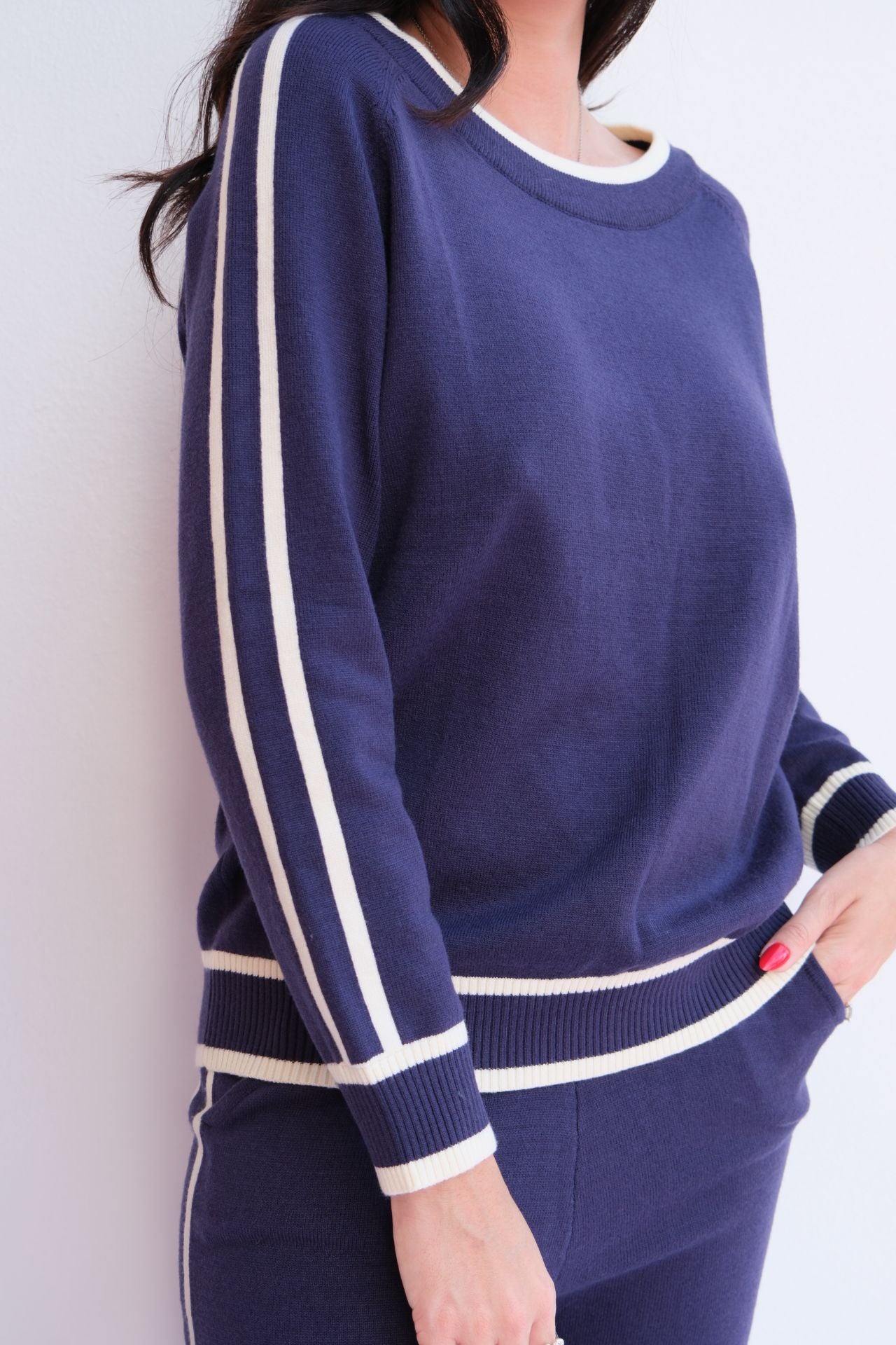 Woman wearing navy knit lounge set with white stripes. 
