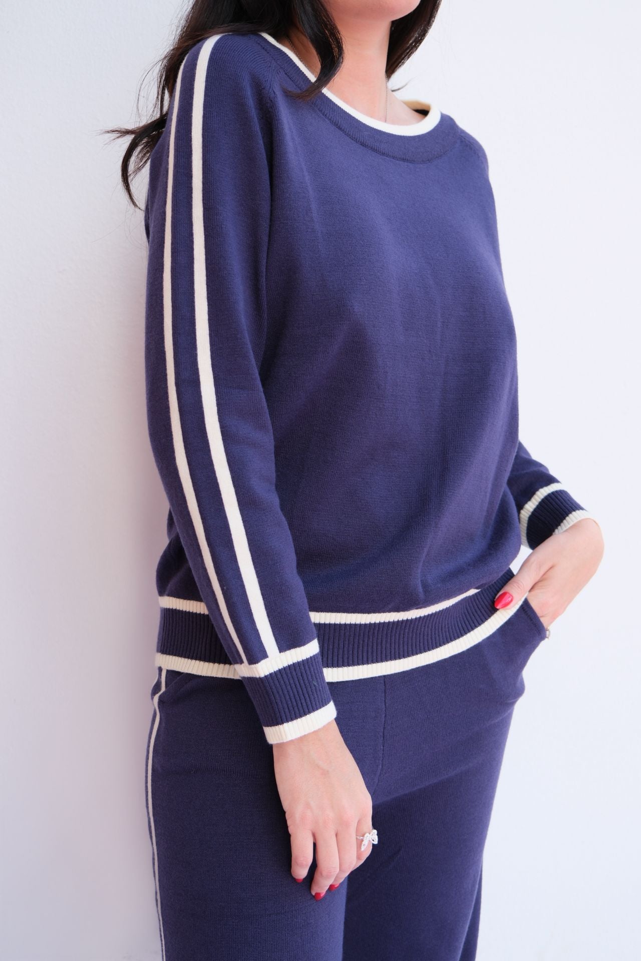 Woman wearing navy knit lounge set with white stripes. 