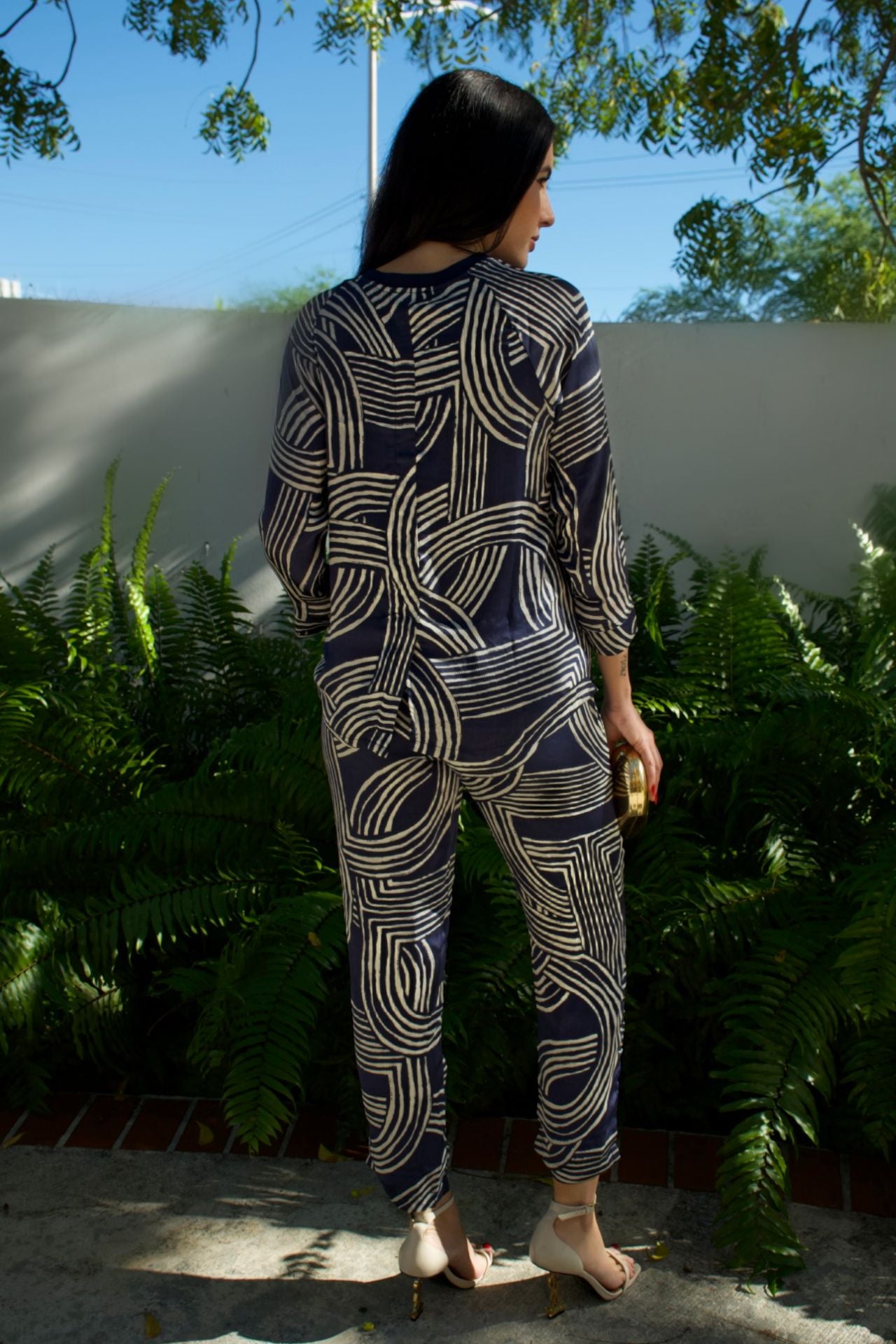 Model wearing navy satin geometric print high-low top and matching pant set — runs large, elegant two-piece outfit Elegance Boutique