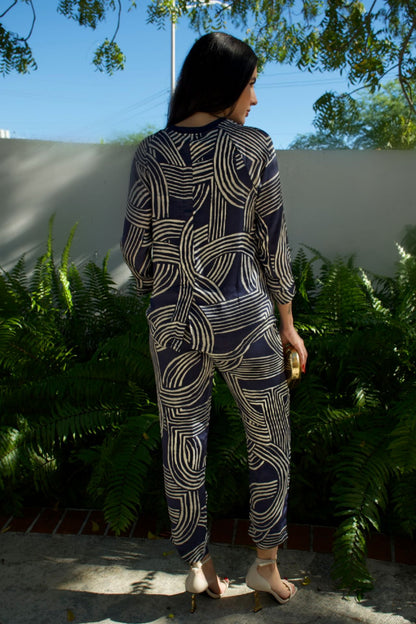 Model wearing navy satin geometric print high-low top and matching pant set — runs large, elegant two-piece outfit Elegance Boutique