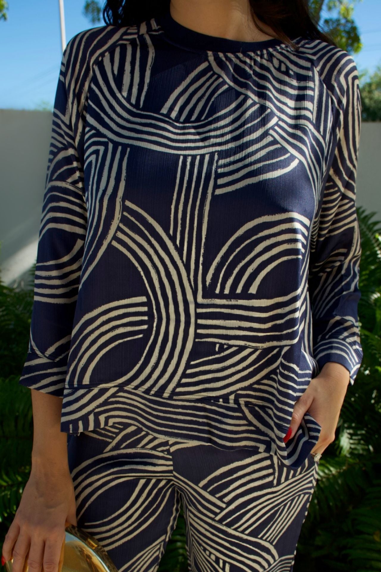 Model wearing navy satin geometric print high-low top and matching pant set — runs large, elegant two-piece outfit Elegance Boutique